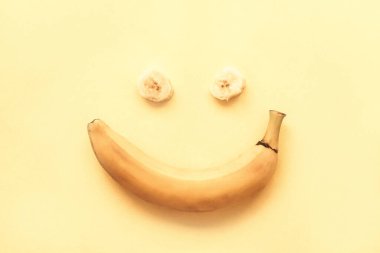 Sarı bir zemin üzerinde muz, gülümseme şeklinde, üst görünüm, düz uzanma.