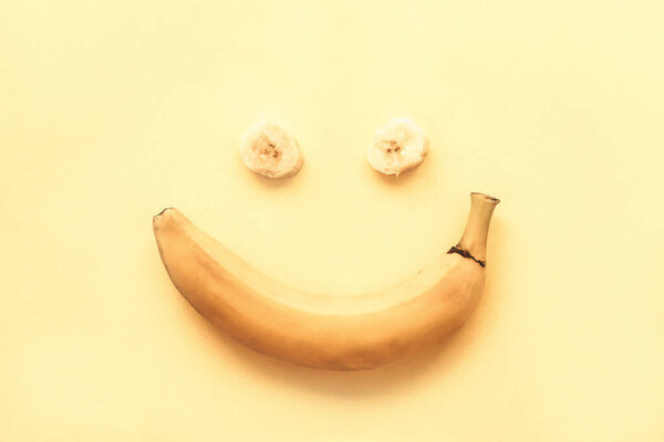 Banana on a yellow background in the form of a smile, top view, flat lay.