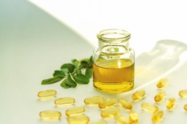 Doğal Omega 3 vitaminleri, cam kavanozda balık yağı ve beyaz arka planda kapsüller.
