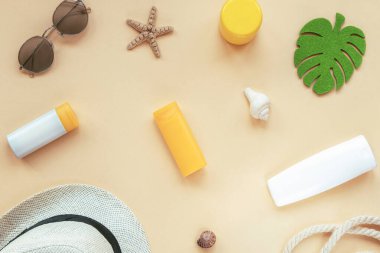 Yüz ve vücut için doğal kozmetik ürünleri, markasız boş paketler, sarı arka planda güneş gözlüğü ve şapka. Üst manzara, düz uzanma