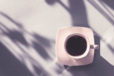 Güneş ışığında bir fincan kahve. Mavi arkaplan, üst görünüm.