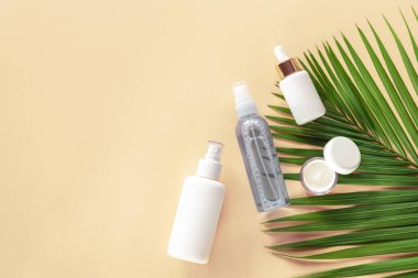 Sarı arka planda yüz ve vücut bakımı kozmetik şişeleri. Serum, nemlendirici, krema kavanozu işaretlenmemiş boş paketler.
