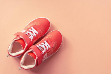 Mercan pembe arka planda turuncu spor ayakkabılar. Sağlıklı yaşam, spor ve eğitim kavramı