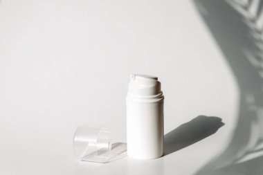 Kozmetik ürünleri dağıtıcısı. Cilt bakımı ve güzellik konsepti. Tropik bitkilerin gölgeleri ile beyaz arkaplan