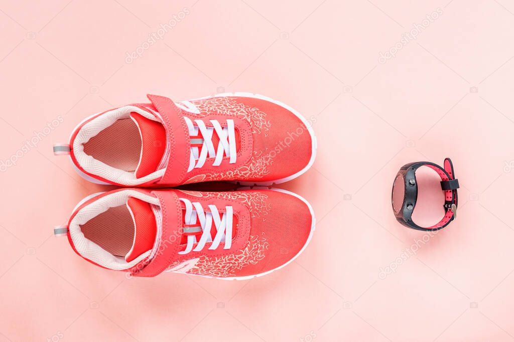 Red sneakers and sport watch on pink background. Concept of healthy life, sport and training, top view, flat lay