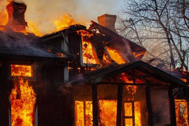 Old wooden house on fire. clipart