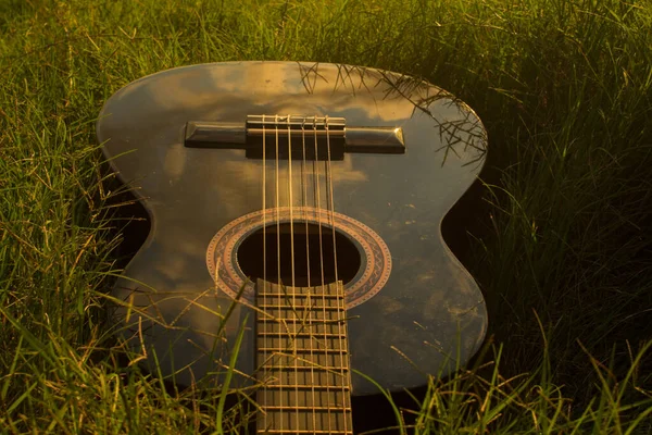 Günbatımında çimlerde siyah gitar