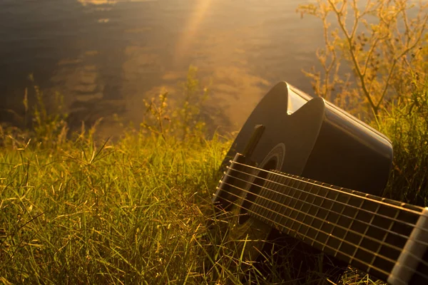 Günbatımında çimlerde siyah gitar