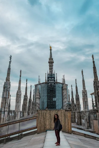 Arka planda Madonnina 'nın zirvesi olan Milan Katedrali' nin çatısındaki kameraya bakan genç bir kadın.