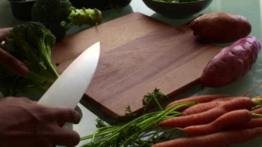 Tahtada sebze doğrayan eller.