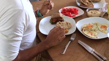 Adam sandviç ve domates yemeye hazırlanıyor.