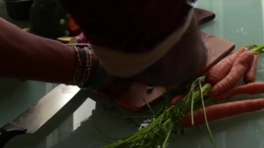 Kesme tahtasında taze bitkiler doğrayan eller.