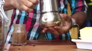 Evde tereyağlı espresso yapan biri.