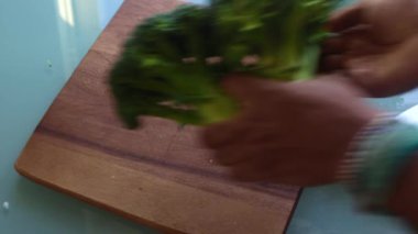 Tahta üzerinde brokoli kesen üst düzey bir kişi