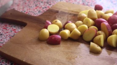 Evde pişirmek için bebek patatesleri doğrayan birini yakın.