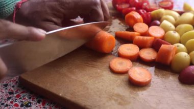 Ahşap doğrama tahtasındaki sebzeleri hazırlayan insanların yakın çekimi.