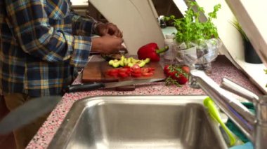 Evdeki mutfakta taze sebze doğrayan bir adam. Çift yemekli 8 saniyelik video.