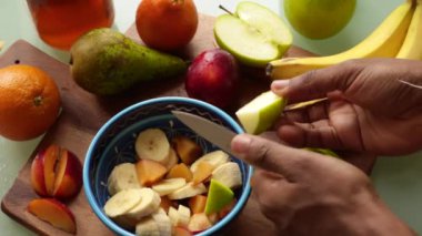 Üst düzey yetişkin evde sağlıklı meyve salatası yapıyor.
