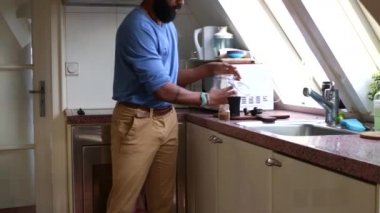 Adam evde elle kavrulmuş kahve çekirdeklerini öğütüyor.