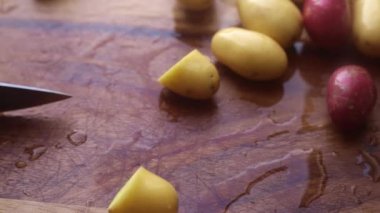 Elleri organik bebek patateslerini evdeki mutfakta tahta kesme tahtasında hazırlıyor.