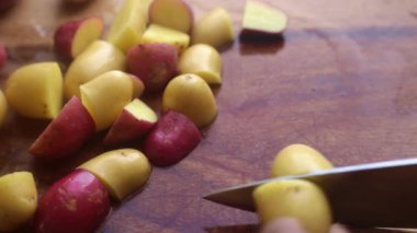 Elleri organik bebek patateslerini evdeki mutfakta tahta kesme tahtasında hazırlıyor.