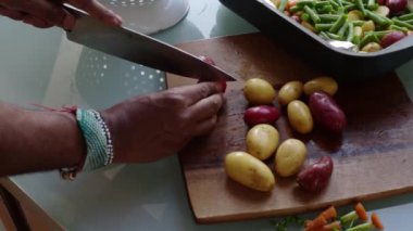 Tahta kesme tahtasında taze sebze hazırlayan kişi.