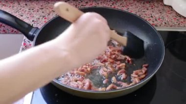 Mutfakta Carbonara makarnası için domuz pastırması kızartıyorum.