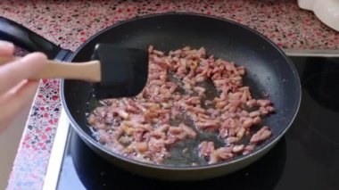 Mutfakta Carbonara makarnası için domuz pastırması kızartıyorum.