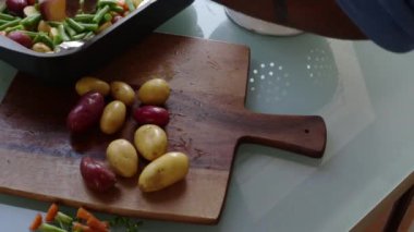 Ahşap doğrama tahtasındaki sebzeleri hazırlayan insanların yakın çekimi.