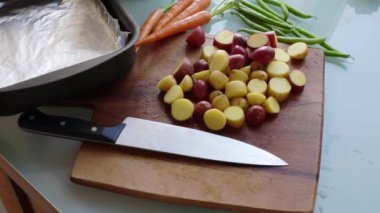 Ahşap doğrama tahtasındaki sebzeleri hazırlayan insan elleri