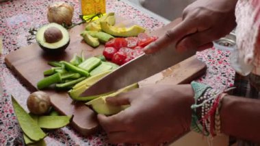 Ahşap kesim tahtasında sebze hazırlayan insanlar.