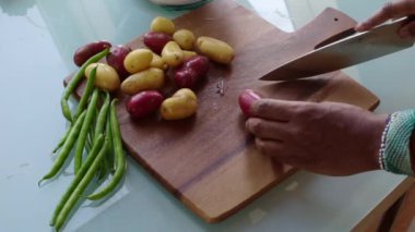 Ahşap kesim tahtasında sebze hazırlayan insanlar.