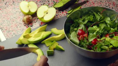 Close up of person preparing fresh avocado salad with apple in kitchen