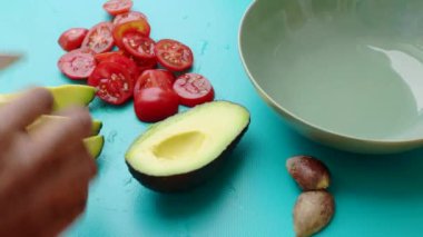 Avokadoyu mutfakta vejetaryen yemeğine hazırlayan kişi.