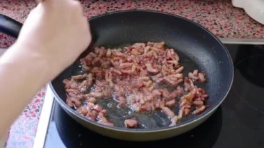 Carbonara soslu makarna için pastırma kızartan kadın. 