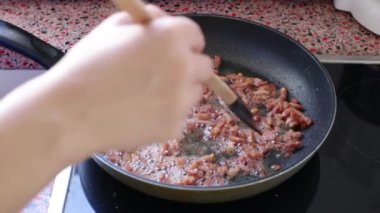 Carbonara soslu makarna için pastırma kızartan kadın. 