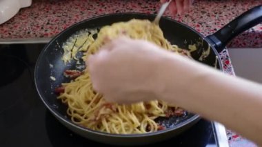Kızartma tavasında lezzetli carbonara makarnası yapan kişi.