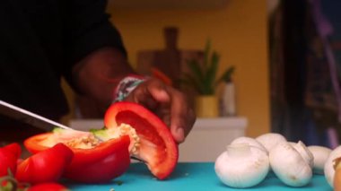 Erkek elleri doğrama tahtasında kırmızı biber hazırlıyor.