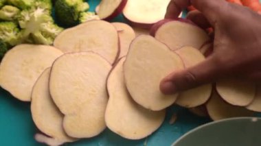 Elleri kesme tahtasında organik tatlı patatesler hazırlıyor.