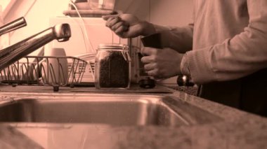 Evdeki mutfakta elle kavrulmuş kahve çekirdeklerini öğüten kişi. 