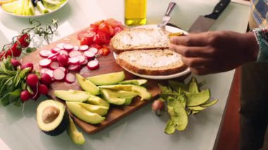 Sağlıklı vejetaryen tartinli sandviç yapan kişi.