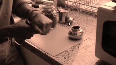 Yetişkinler evde elle kavrulmuş kahve çekirdeklerini öğütüyor.