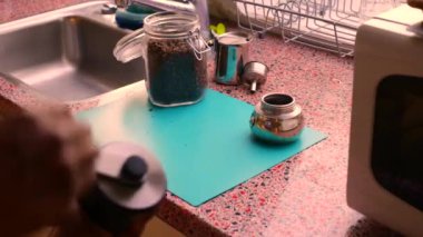 Evdeki mutfakta elle kavrulmuş kahve çekirdeklerini öğüten kişi.