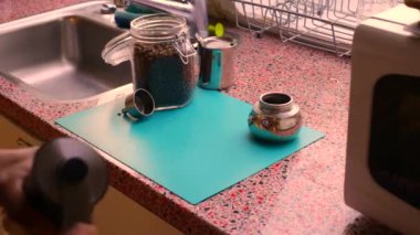 İnsan elleri evde elle kavrulmuş kahve çekirdeklerini öğütüyor.      