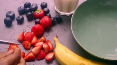 Elleri ahşap kesim tahtasında meyve hazırlıyor.