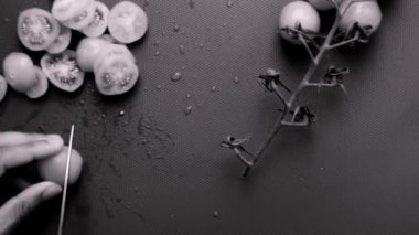 Kiraz domateslerini doğrama tahtasında hazırlayan kişi.