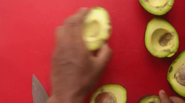 Avokadoları doğrama tahtasında hazırlayan kişinin üst görünümü