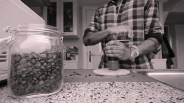 Evde elle kavrulmuş kahve çekirdeklerini öğüten biri var.