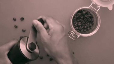 Kırmızı arka planda kahve çekirdeklerini elle öğüten kişi.