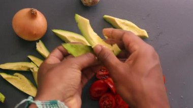 Mutfakta vişneli domates ve avokado hazırlayan kişi.